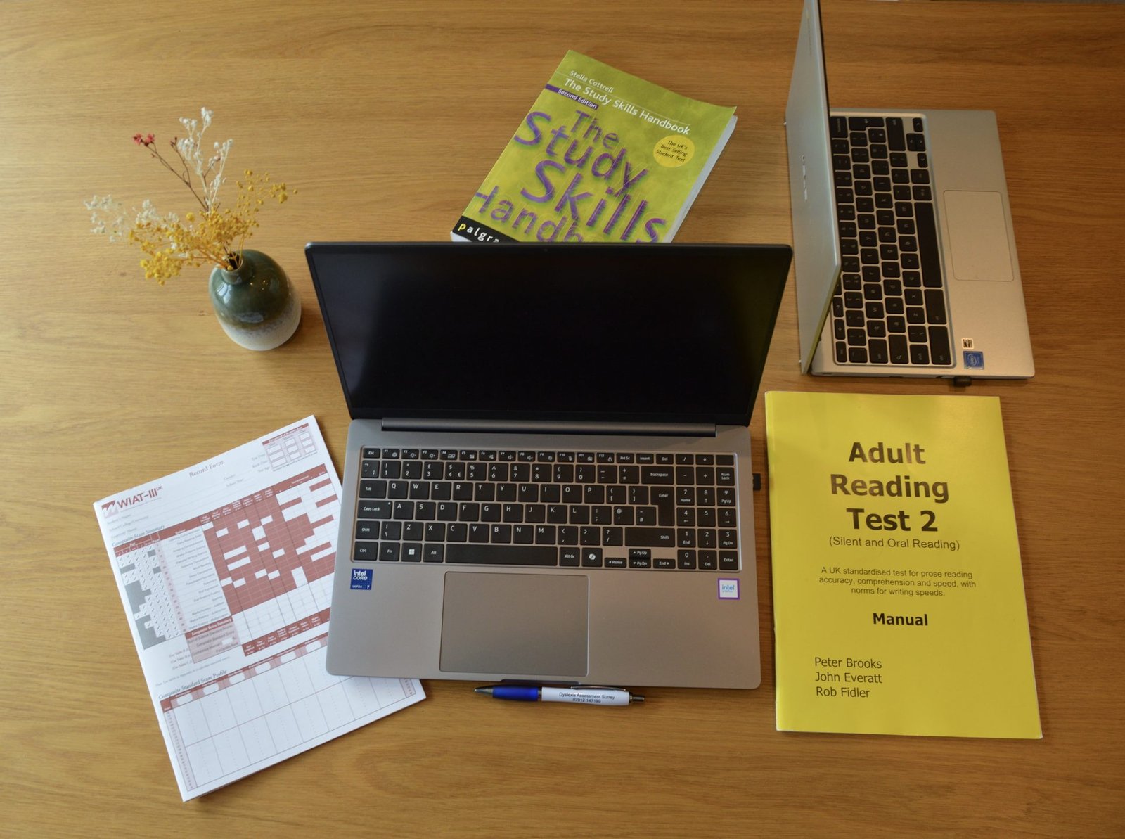 A laptop and an adult reading-test booklet laid out on the table