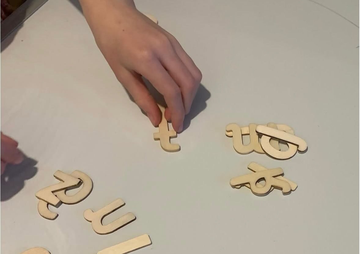A hand arranging wooden letters to build a word